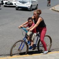 Mor med siddende søn på tværstangen af cyklen